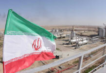 Nuclear Alarm: IRGC-Linked Outlet Urges Iran to Build the Bomb Iranian flag near an industrial gas refinery.