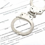 Congressional Candidate Arrested in Hawaii—Allegedly Pulls Gun Handcuffs on top of an arrest warrant document.