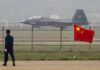 Betrayal Playbook: Vets Train China’s Aces? Jet with 31001 marking behind barbed wire fence.