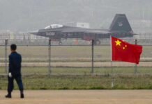 Betrayal Playbook: Vets Train China’s Aces? Jet with 31001 marking behind barbed wire fence.