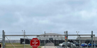 Chain-link fence with Restricted Area Stop No Photography sign.