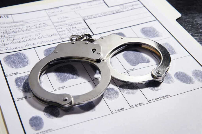 608376650 Handcuffs on fingerprint form with fingerprints visible.