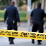 Triple Homicide Mystery, Evidence Still Sealed Police officers walking past caution tape at a crime scene