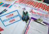 Voter registration table with forms, pens, and brochures.