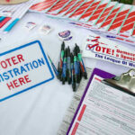 Voter registration table with forms, pens, and brochures.