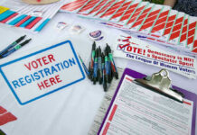 Poll Twist: Flag Wars Explode Voter registration table with forms, pens, and brochures.