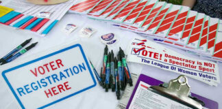 Voter registration table with forms, pens, and brochures.