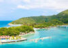 Tourist Paradise, Chilling Warning Tropical beach with docks and lush green hills.