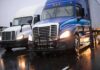 Two semi trucks driving side by side on a wet highway