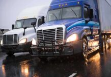 Two semi trucks driving side by side on a wet highway