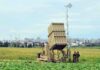 Military defense system deployed in a field with soldiers nearby