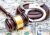 Judge's gavel and handcuffs on pile of US dollar bills