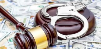 Judge's gavel and handcuffs on pile of US dollar bills