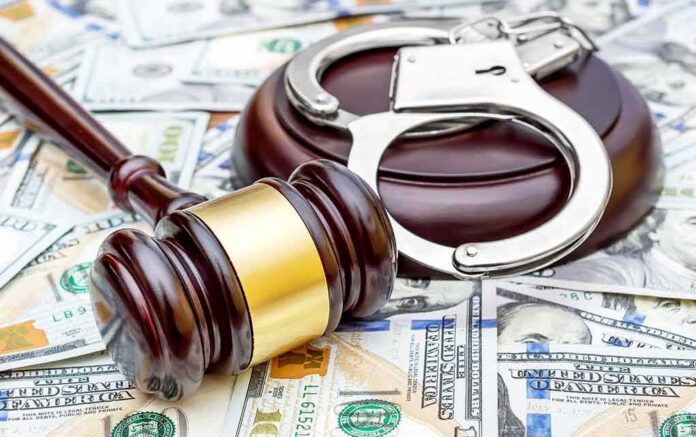 Judge's gavel and handcuffs on pile of US dollar bills