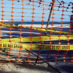 Orange safety net and yellow police tape blocking a beach access