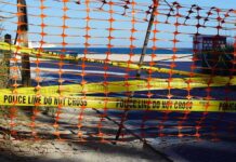 Orange safety net and yellow police tape blocking a beach access