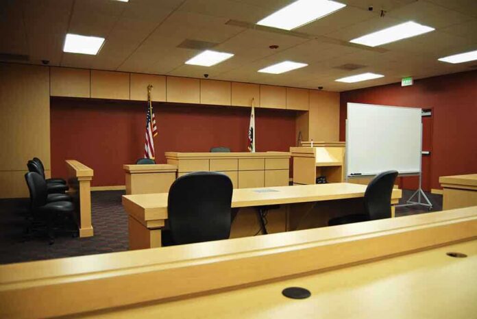 Interior view of an empty courtroom with wooden furniture and American flags