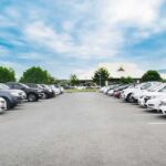 Parking lot lined with cars under a blue sky