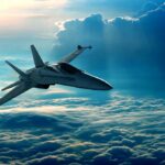 A fighter jet flying above the clouds during sunset