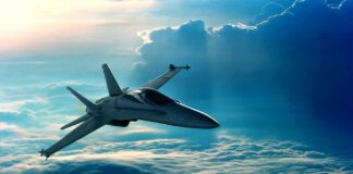 A fighter jet flying above the clouds during sunset