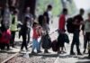 People with bags walking along railway tracks
