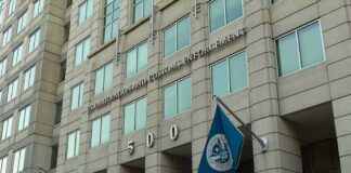 U.S. government building facade with American and blue departmental flags