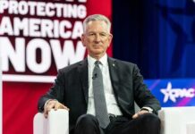 man in suit seated on stage during conference