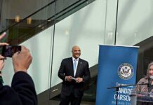 Citizenship Proposal Leaves Key Rules Unclear Man in a suit at a public event near a blue banner