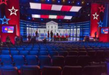 Debate stage with red and blue lighting and empty audience seats