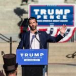 Donald Trump Jr. speaks at an outdoor rally podium