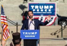 Donald Trump Jr. speaks at an outdoor rally podium