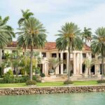 Waterfront mansion with palm trees and grand columns