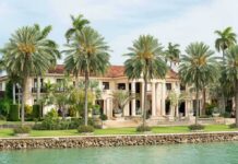 Waterfront mansion with palm trees and grand columns