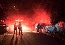 Firefighters and police at a nighttime car fire scene