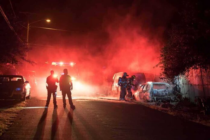 Firefighters and police at a nighttime car fire scene