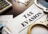 Thousands Leave New York Amid Budget Concerns Handcuffs and calculator on tax evasion document