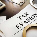 Handcuffs and calculator on tax evasion document