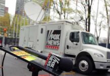 Fox News microphone and satellite truck on city street